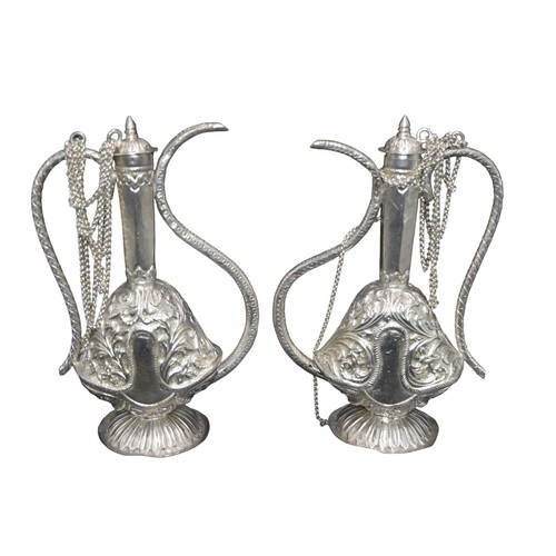 822 - A PAIR OF PERSIAN STYLE SILVER EWERS, elegant scrolling handles and spout, the body with scroll foli... 