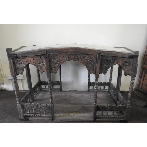 31 - A CARVED INDIAN HARDWOOD PALANQUIN, the canopy raised on bobbin turned supports, above a galleried p... 