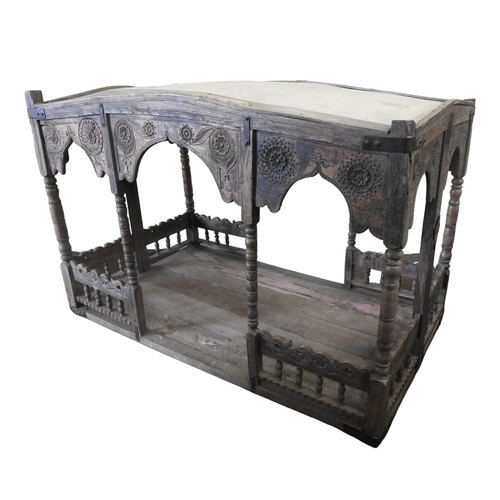 31 - A CARVED INDIAN HARDWOOD PALANQUIN, the canopy raised on bobbin turned supports, above a galleried p... 