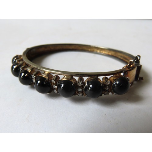 538 - A BLACK DIOPSIDE BANGLE, set with seven circular cabochon-cut stones showing star effect, each space... 