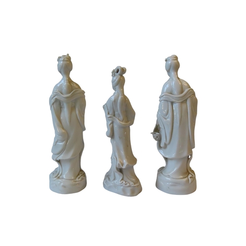 158 - THREE CHINESE BLANC DE CHINE FIGURINES, depicting female courtiers, each modelled standing in flowin... 