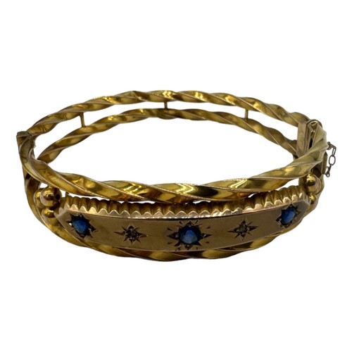 562 - A LATE VICTORIAN 9CT GOLD HOLLOW HINGED BANGLE, CIRCA 1880set with three circular-cut sapphires and ... 