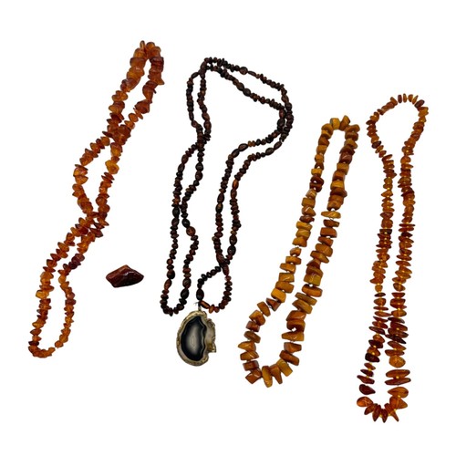 557 - FOUR AMBER NECKLACES AND AN AMBER BROOCH