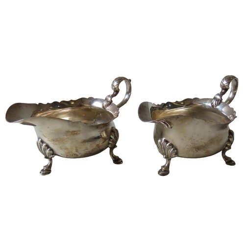 597 - A PAIR OF VINTAGE SILVER SAUCEBOATS, with 'C'-scroll handles, undulating rims, raised on three hoof ... 