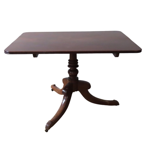 43 - A MAHOGANY SINGLE PEDESTAL DINING TABLE, the tilting rectangular top raised on a ring turned pillar,... 