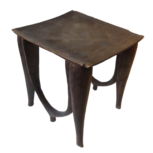 85 - A NUPE STOOL, the square top with carved geometric designs upon four tapering legs, and joined by tw... 