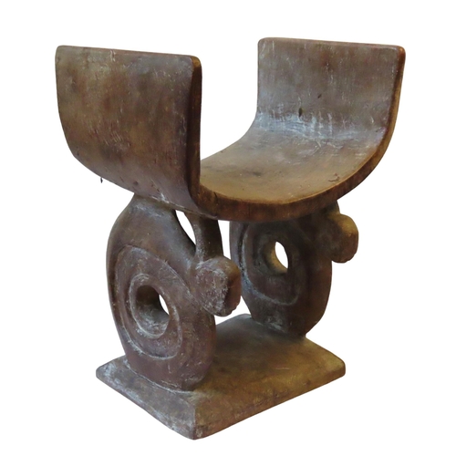 86 - AN AFRICAN STOOL, POSSIBLY ASHANTI, the deep curved seat supported by two coiled snakes. (seat with ... 