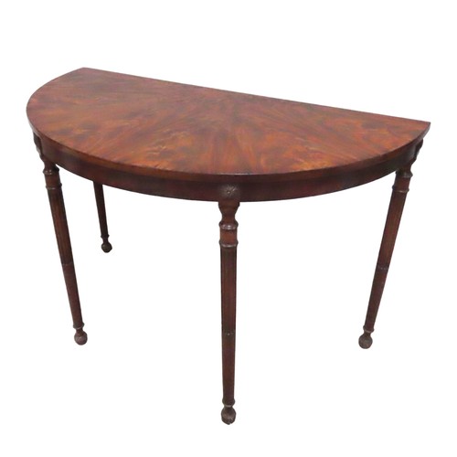 28 - A FIGURED MAHOGANY DEMI LUNE TABLE, 19TH CENTURY, raised on four slender turned fluted legs, termina... 