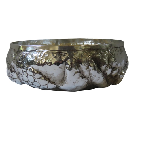 675 - A HAMMERED WHITE METAL FRUIT BOWL, the sides with repousse decoration depicting various fruits11 cm ... 