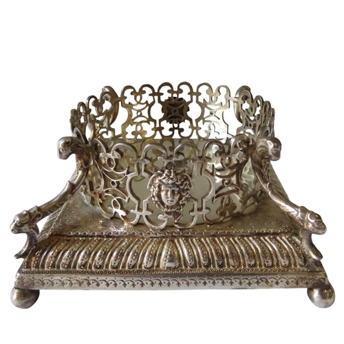 699 - AN ORNATE GEORGE II SILVER BOTTLE STAND, a pierced circular lattice gallery adorned with Neo Classic... 