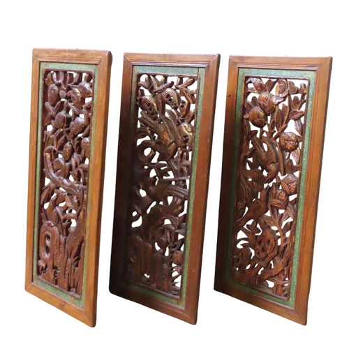 121 - A GROUP OF THREE CARVED CHINESE HARDWOOD PANELS, each depicting various birds perched amongst fruiti... 