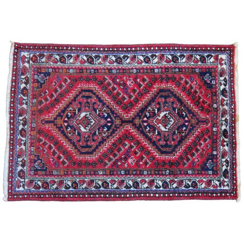 145 - A HAND KNOTTED PERSIAN SHIRAZ RUG, with two open blue medallions on a red ground158 x 111 cmPROVENAN... 