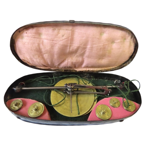 258 - A GEORGIAN POCKET BALANCE IN A LACQUERED OVOID TIN CASE with steel arm and brass pans and wiehgts to... 