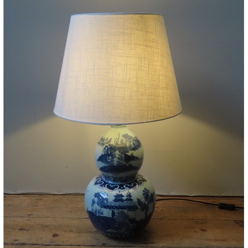 313 - A CHINESE-STYLE BLUE AND WHITE DOUBLE GOURD TABLE LAMP decorated with a palace and rural landscape s... 