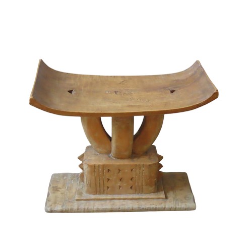 219 - A CARVED ASHANTI STOOL, the bowed rectangular seat on four curved pillars, raised on a chip carved r... 