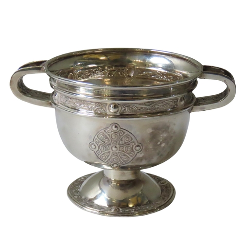 672 - AN IRISH SILVER TWO-HANDLED CUP IN THE FORM OF THE ARDAGH CHALICE, the twin handles, frieze band and... 