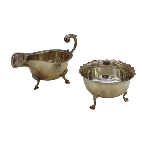 657 - A SILVER SAUCEBOAT AND SUGAR BOWL, the sauceboat with scrolling handle and raised on three hoof feet... 