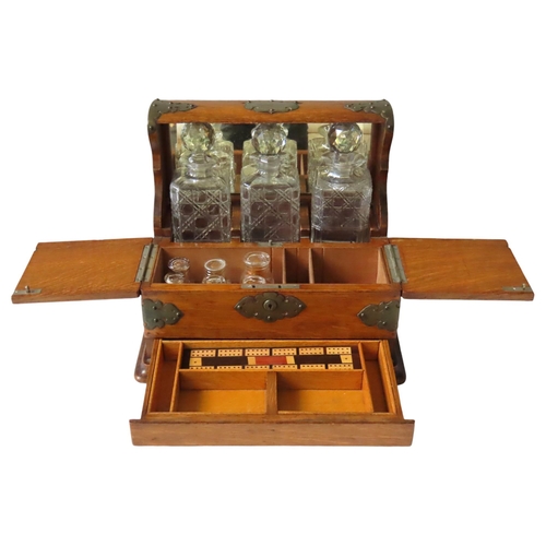 215 - A LATE VICTORIAN OAK TANTALUS, holding three square form cut glass decanters within a mirror backed ... 