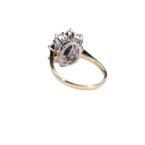 337 - A SAPPHIRE AND DIAMOND CLUSTER RINGthe oval mixed-cut sapphire eight claw set above a bezel of eight... 