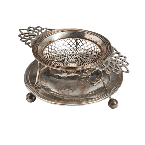 329 - A VINTAGE SILVER TEA STRAINER, the strainer sat upon a galleried circular stand, on ball feet, marke... 