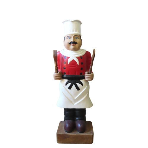 454 - A PAINTED HARDWOOD FIGURE OF A CHEF, modelled standing, holding a spoon and fork, raised on a rectan... 