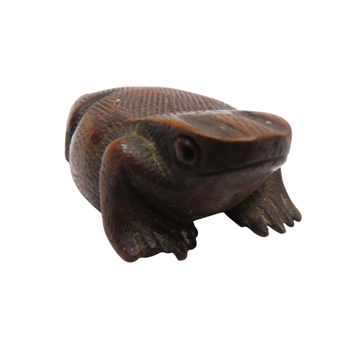 303 - A NAIVE WOODEN SNUFF BOX IN THE FORM OF A TOAD with hinged base and glass eyes7cms long