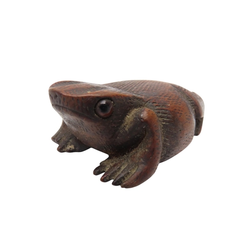 303 - A NAIVE WOODEN SNUFF BOX IN THE FORM OF A TOAD with hinged base and glass eyes7cms long