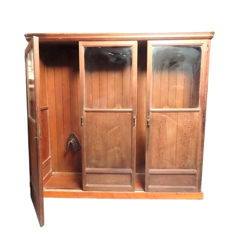 25 - A LARGE PINE BIBLIOTHEQUE, ogee cornice over three part glazed cabinet doors, raised on a plinth bas... 