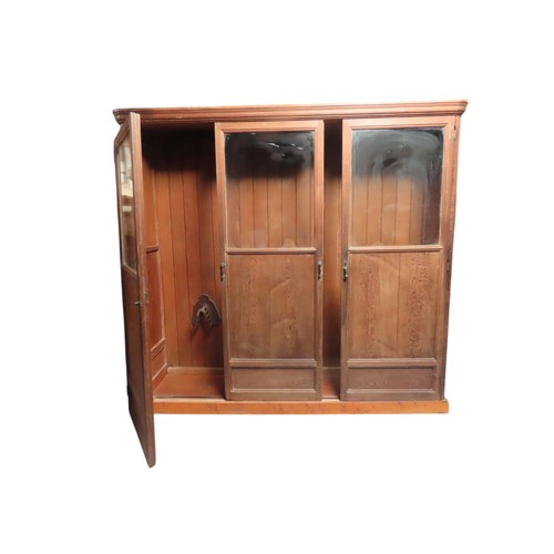 25 - A LARGE PINE BIBLIOTHEQUE, ogee cornice over three part glazed cabinet doors, raised on a plinth bas... 