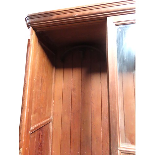 25 - A LARGE PINE BIBLIOTHEQUE, ogee cornice over three part glazed cabinet doors, raised on a plinth bas... 