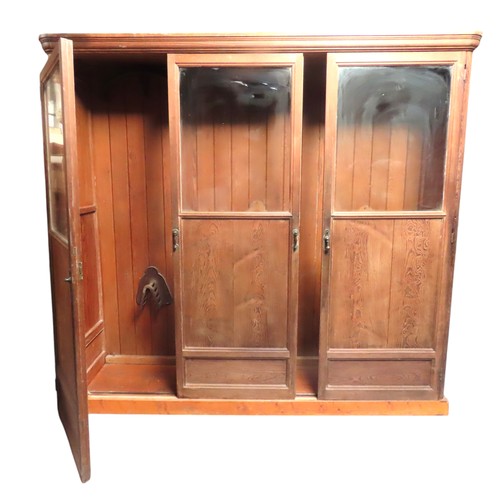 25 - A LARGE PINE BIBLIOTHEQUE, ogee cornice over three part glazed cabinet doors, raised on a plinth bas... 