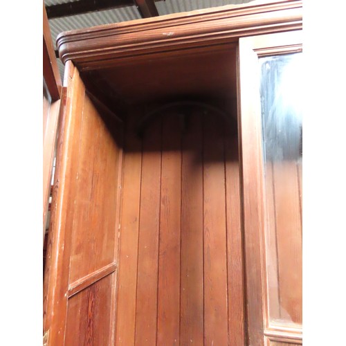 25 - A LARGE PINE BIBLIOTHEQUE, ogee cornice over three part glazed cabinet doors, raised on a plinth bas... 