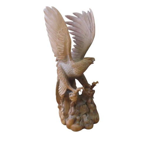 24 - A VERY LARGE IMPRESSIVE CARVED PINE EAGLE, modelled taking flight from a rocky outcrop, with wings s... 