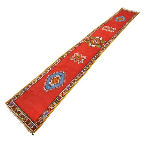 134 - HANDWOVEN WOOLEN RUNNER Red ground with faun and blue border 492cm x 75cmPROVENANCE: From The Heming... 