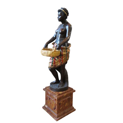 507 - A 19TH CENTURY TERRACOTTA BLACKAMOOR, modelled standing, holding a fruit basket, raised on a plinth ... 