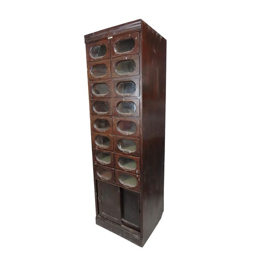 48 - A VINTAGE HABERDASHER'S STORAGE UNITcomprised of 16 glass fronted drawers over two sliding doors, be... 