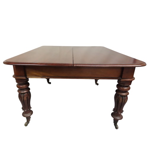 34 - A MAHOGANY DRAW-LEAF DINING TABLEMID 19TH CENTURYraised on tulip carved baluster legs, terminating i... 