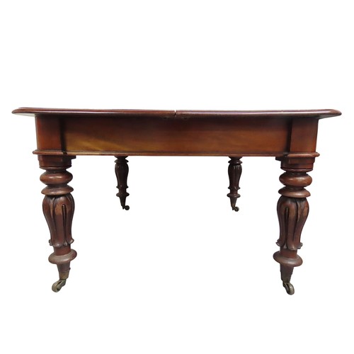34 - A MAHOGANY DRAW-LEAF DINING TABLEMID 19TH CENTURYraised on tulip carved baluster legs, terminating i... 
