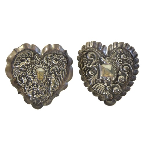 55 - TWO EDWARDIAN SILVER HEART SHAPED REPOUSSE DISHESwith putti and bird decoration(9.8 x 10.7 cm max)to... 