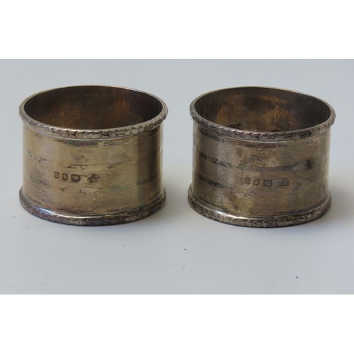 31 - A MIXED GROUP OF FOUR SILVER NAPKIN RINGSconsisting of a pair of engine turned rings and two planish... 