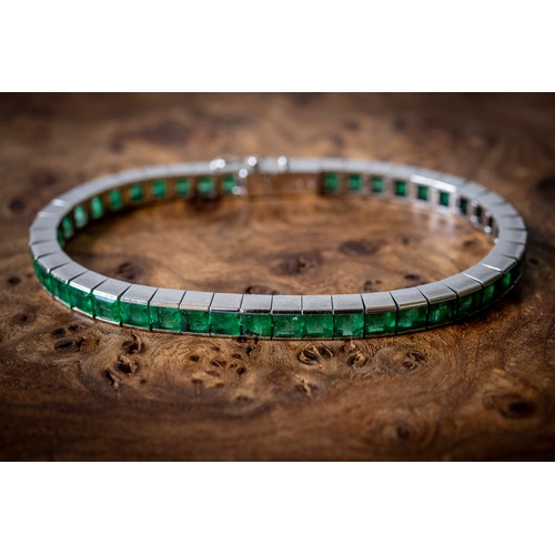 216 - AN ART DECO EMERALD BRACELET,the uniform row of step-cut emeralds in articulated settings, concealed... 