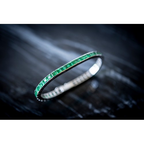 216 - AN ART DECO EMERALD BRACELET,the uniform row of step-cut emeralds in articulated settings, concealed... 