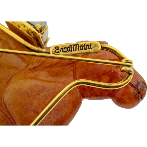 237 - A MULTI GEM SET HORSE BROOCH BY IRADJ MOINI, the orange hardstone horse seated upon a carved soapsto... 