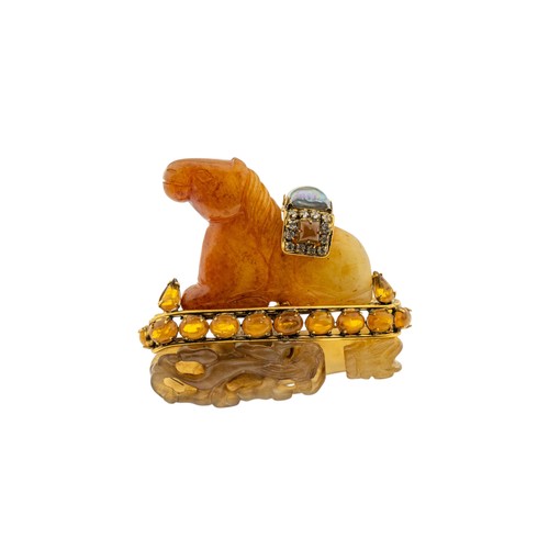 237 - A MULTI GEM SET HORSE BROOCH BY IRADJ MOINI, the orange hardstone horse seated upon a carved soapsto... 