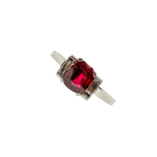 227 - A RED SPINEL AND DIAMOND RING,the oval cut red spinel in a four claw setting, between two baguette c... 