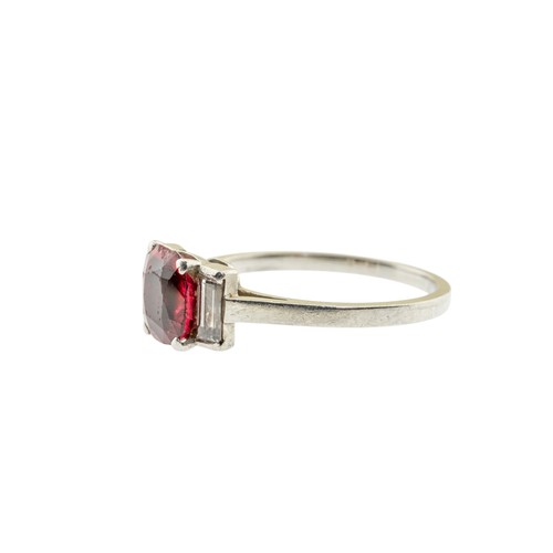 227 - A RED SPINEL AND DIAMOND RING,the oval cut red spinel in a four claw setting, between two baguette c... 