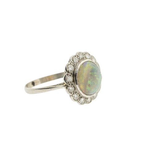 212 - AN EARLY 20TH CENTURY OPAL AND DIAMOND RING, the circular cabochon opal, in a collet setting, within... 