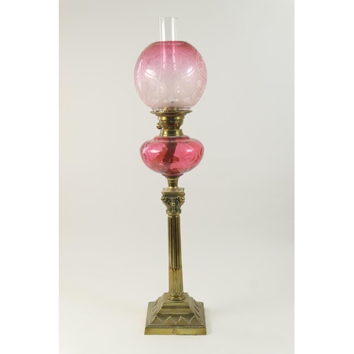 422 - Edwardian brass and cranberry glass pedestal oil lamp, the globular shade etched with flowers in Art... 