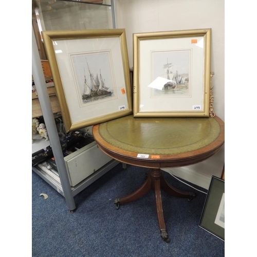 293 - Green leather topped circular occasional table on castors; also two framed prints of masted fishing ... 