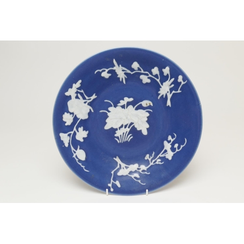 88 - Chinese blue ground dish, 19th Century, slip decorated with white foliate sprays around a lotus cent... 